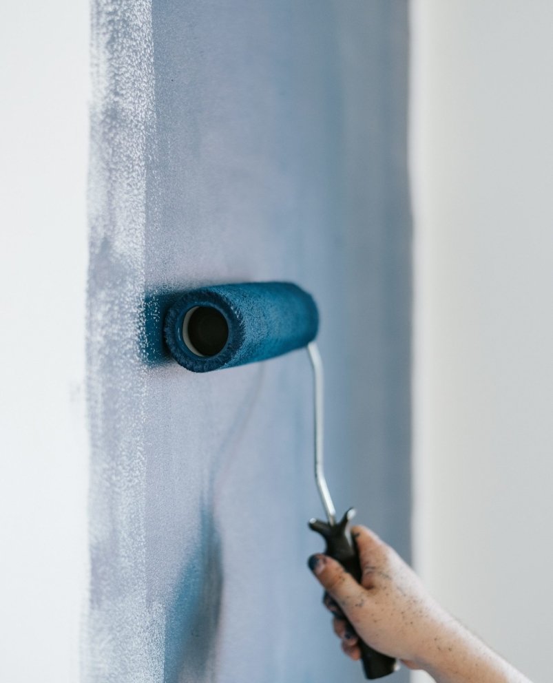 A closeup shot of a female using paint rollers with the color blue
